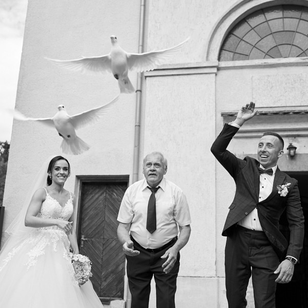 Zenich s nevestou vypustajuci holubky po obrade v kostole