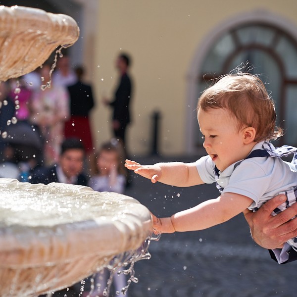 Chlapcek hrajuci sa s kvapkami vody vo fontane na nadvori zamku Simak v Pezinku